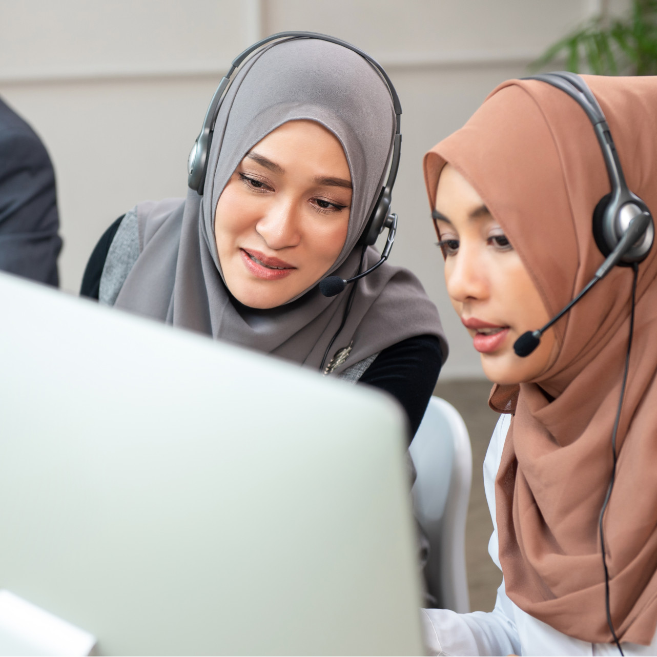 Two females in hijab working together in front of a computer