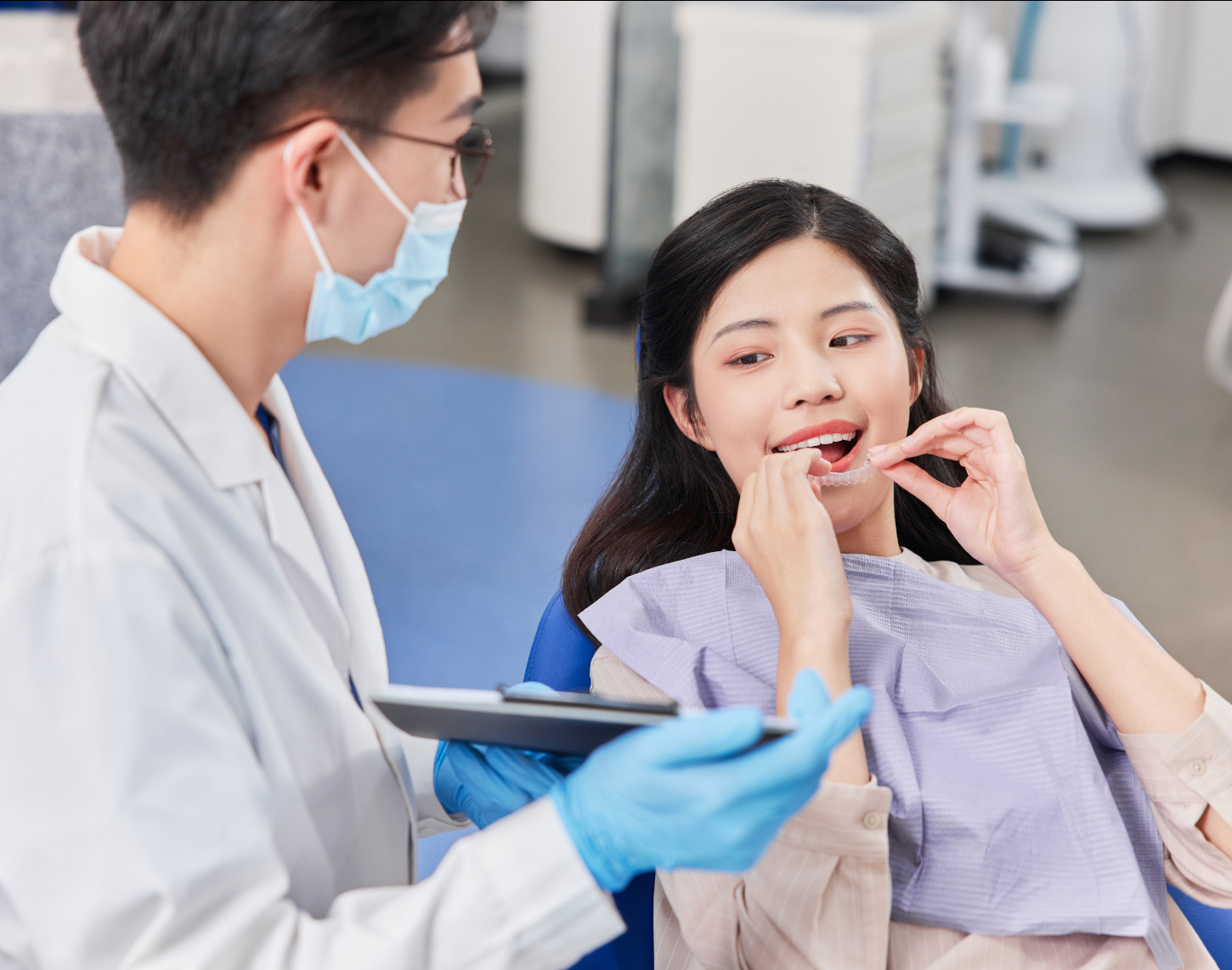 Dentist in a mask examining a female patient's teeth in a dental clinic