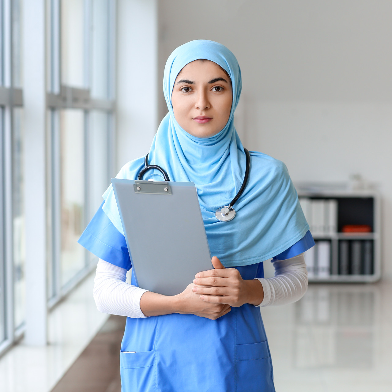 Confident female healthcare professional in hijab holding a clipboard