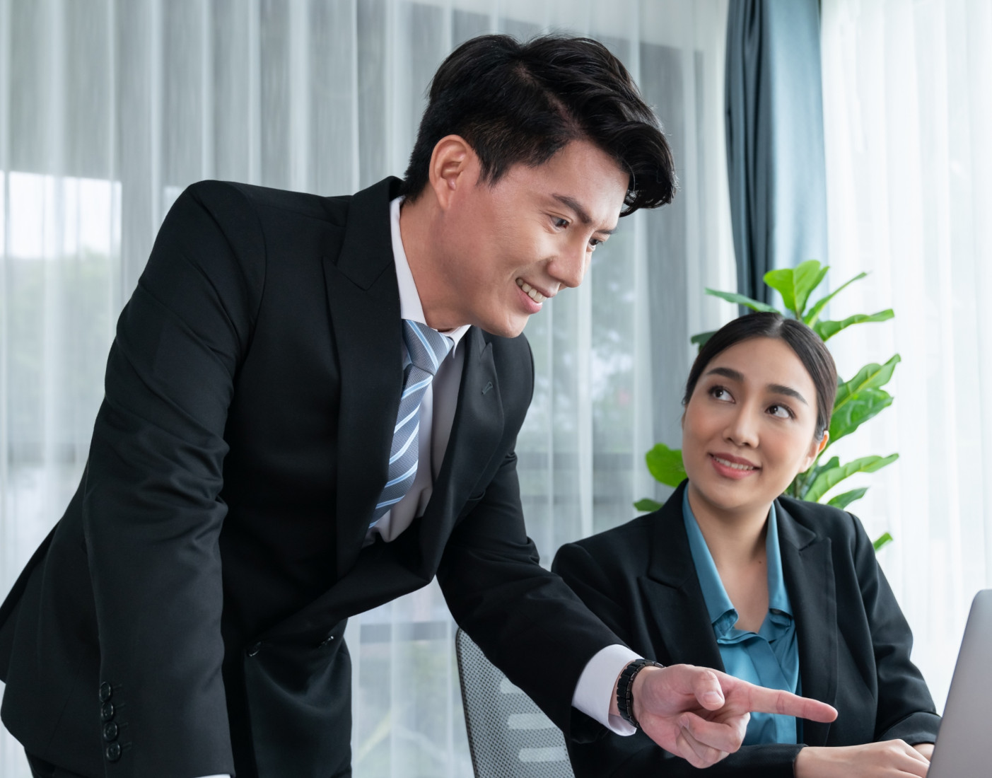 Professional man and woman discussing over a laptop in a bright office