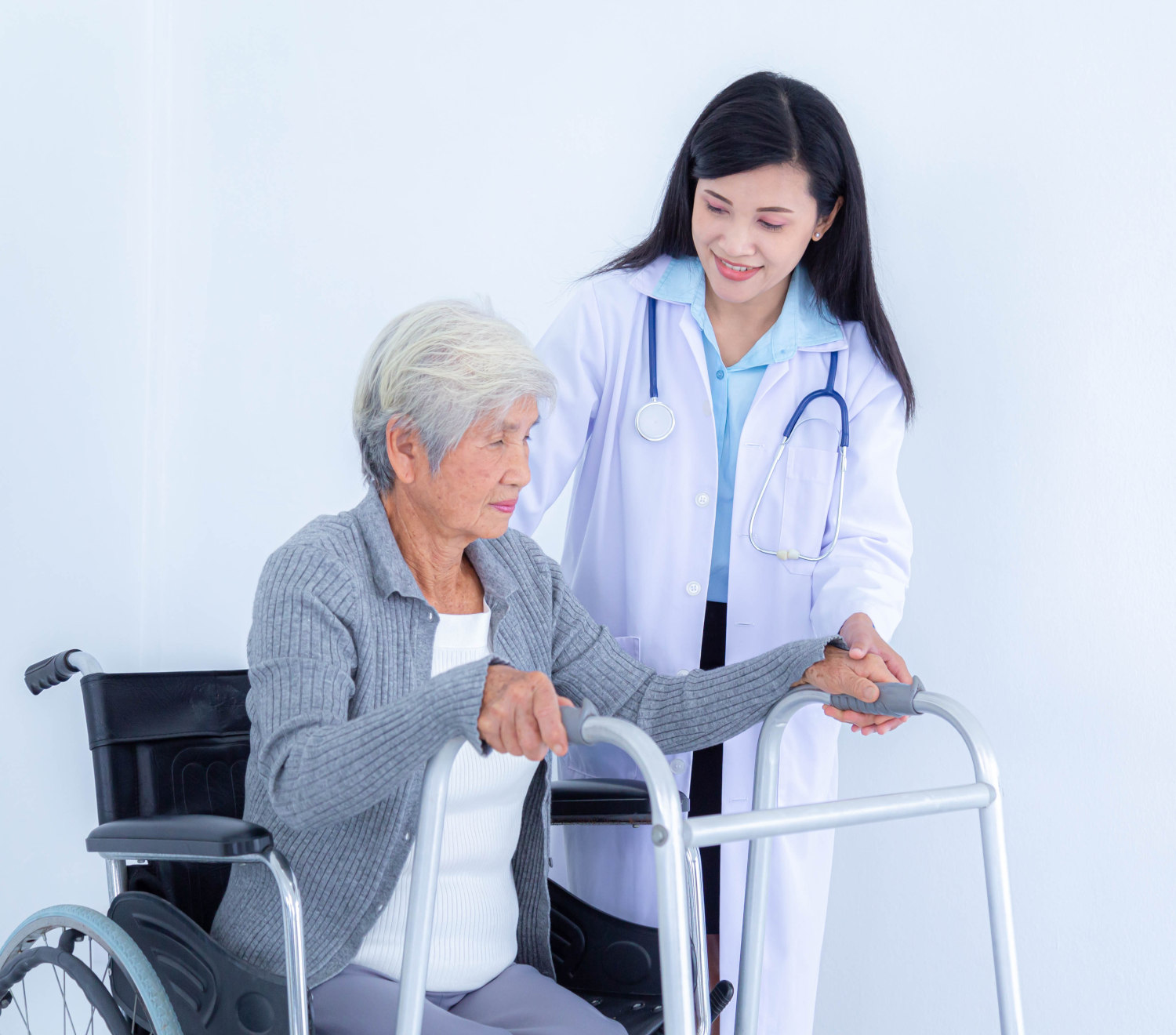 Female doctor assisting an elderly woman using a walker, with a wheelchair in the background