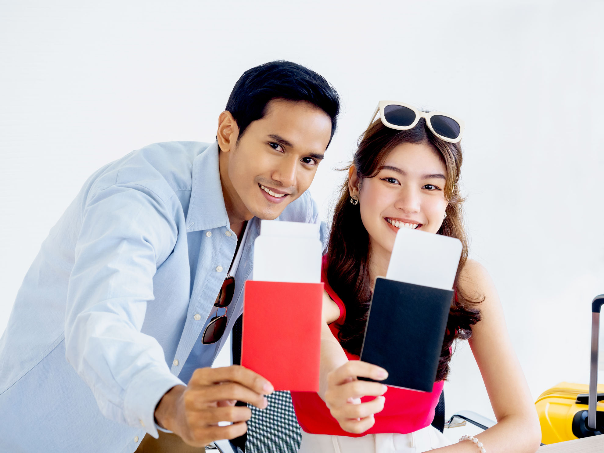 Cheerful young couple holding passports with a yellow suitcase, ready for travel